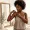 Woman with deep brown skin adjusting a bra strap near a mirror
