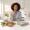 Woman with warm brown skin choosing between two different meals at a kitchen counter